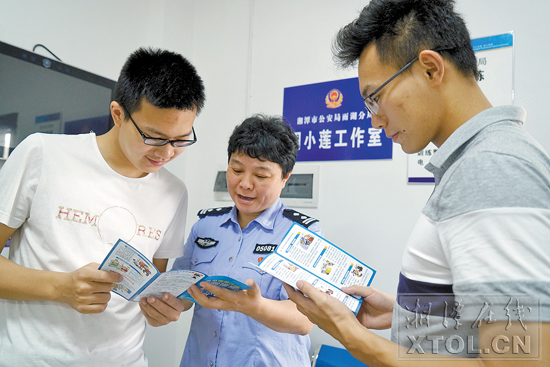 周小莲提醒来警务室办事的大学生防范电信诈骗。(记者 刘建强 摄)